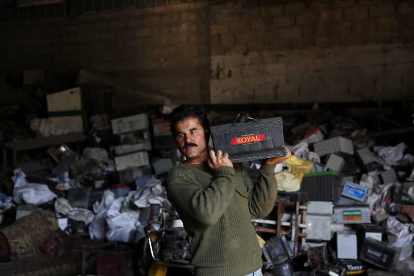A Palestinian worker carries a discarded battery at a warehouse in Jebaliya, Gaza Strip, Wednesday, Dec. 15, 2021. In a territory suffering from chronic power outages, batteries are needed to keep most Gaza households running. But huge mounds of used batteries are piling up at makeshift outdoor landfills, posing a threat to public health and the environment. (AP Photo/Adel Hana)