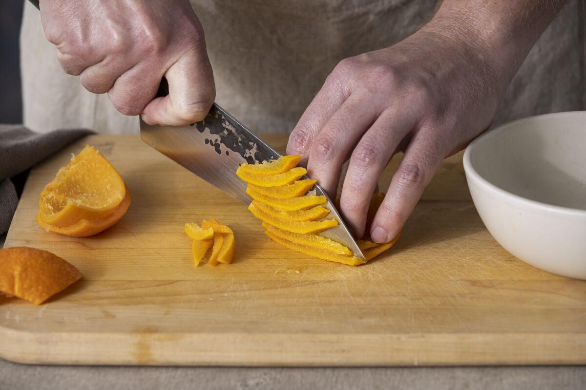 LOS ANGELES, CALIFORNIA, Jan. 19, 2022: Step-by-step citrus marmalade-cooking guide: slicing cooked Seville oranges peels