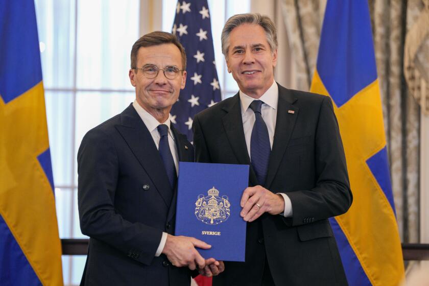 Secretary of State Antony Blinken, right, poses for a photo with Swedish Prime Minister Ulf Kristersson holding Sweden's NATO Instruments of Accession in the Benjamin Franklin Room at the State Department, Thursday, March 7, 2024, in Washington. (AP Photo/Jess Rapfogel)