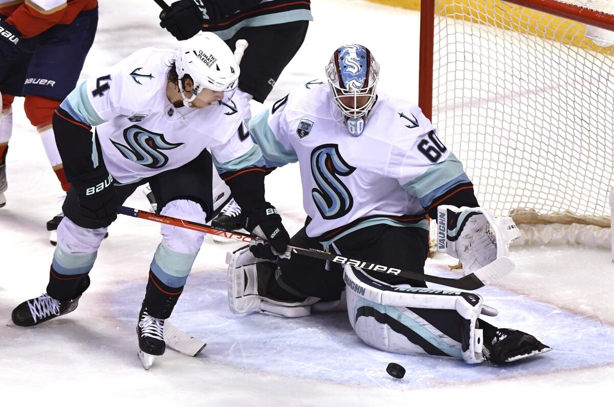 Seattle Kraken goaltender Chris Driedger (60) makes a save against the Florida Panthers next to defenseman Haydn Fleury (4) during the second period of an NHL hockey game Saturday, Nov. 27, 2021, in Sunrise, Fla. (AP Photo/Jim Rassol)