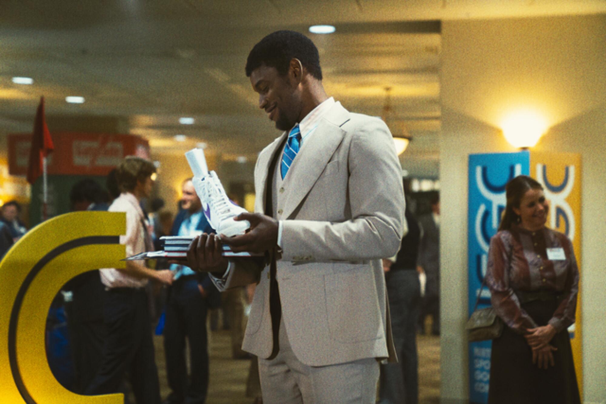 A man in a white suit examines a Nike high-top shoe.