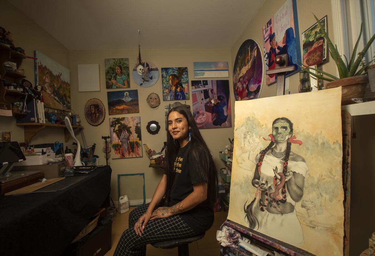 An artist sits beside a painting in progress.