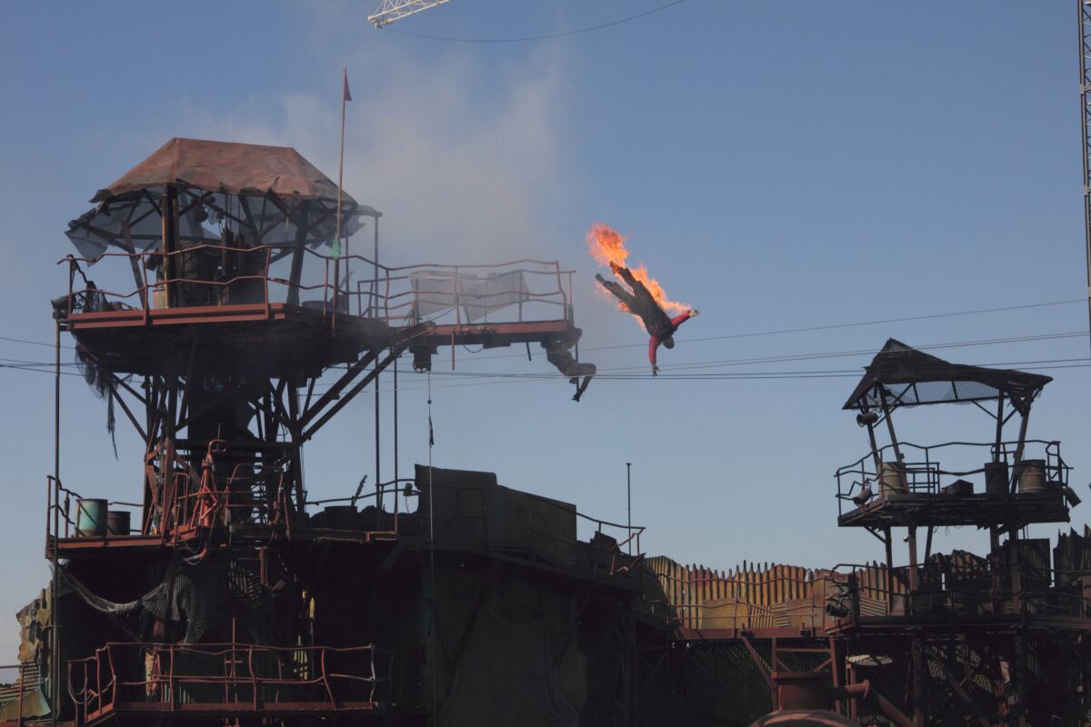 A stunt performer does a high dive while on fire during a theme-park live-action show