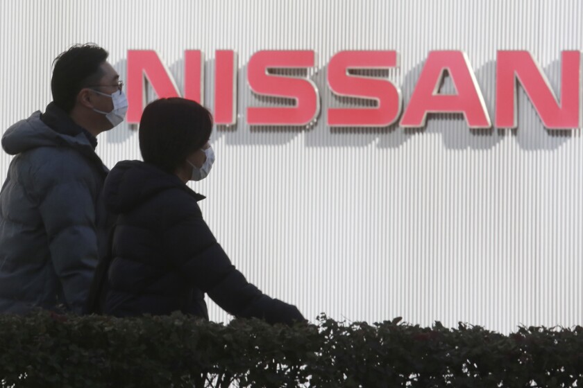 People walk past the corporate logo at Nissan Motor Co.'s global headquarters in Yokohama, near Tokyo, Tuesday, Feb. 9, 2021. Japanese automaker Nissan reported Tuesday losses for the fiscal third quarter, as its sales were hit by the coronavirus pandemic and its brand image continued to take a beating from the financial misconduct scandal centered on its former chairman, Carlos Ghosn. (AP Photo/Koji Sasahara)