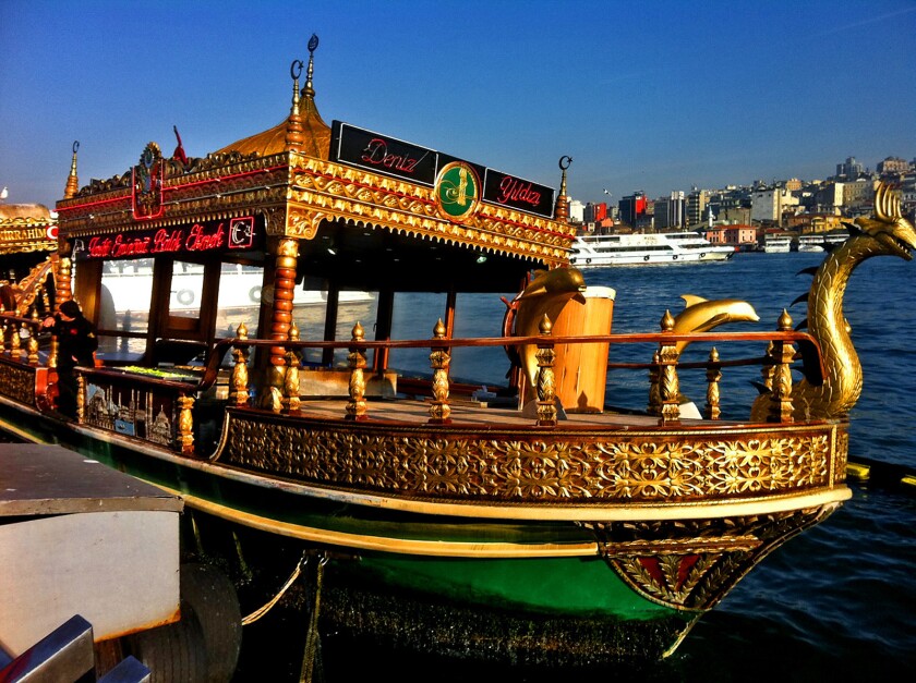Colorful fishing boats beneath Galata Bridge in Istanbul.