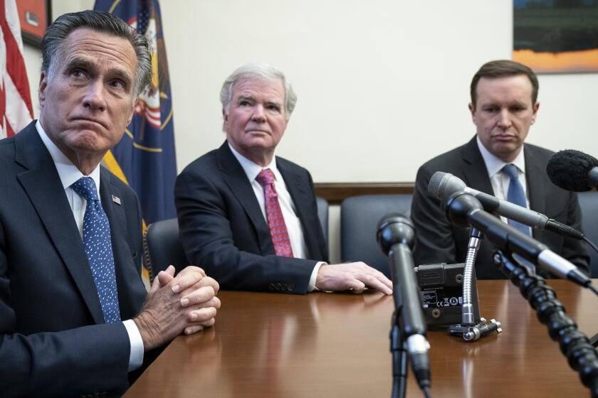 NCAA President Mark Emmert is flanked by Sens. Mitt Romney, left, and Chris Murphy during a news conference.