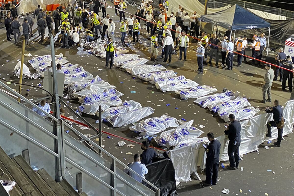 Two rows of victims' bodies lie covered in plastic on the ground.