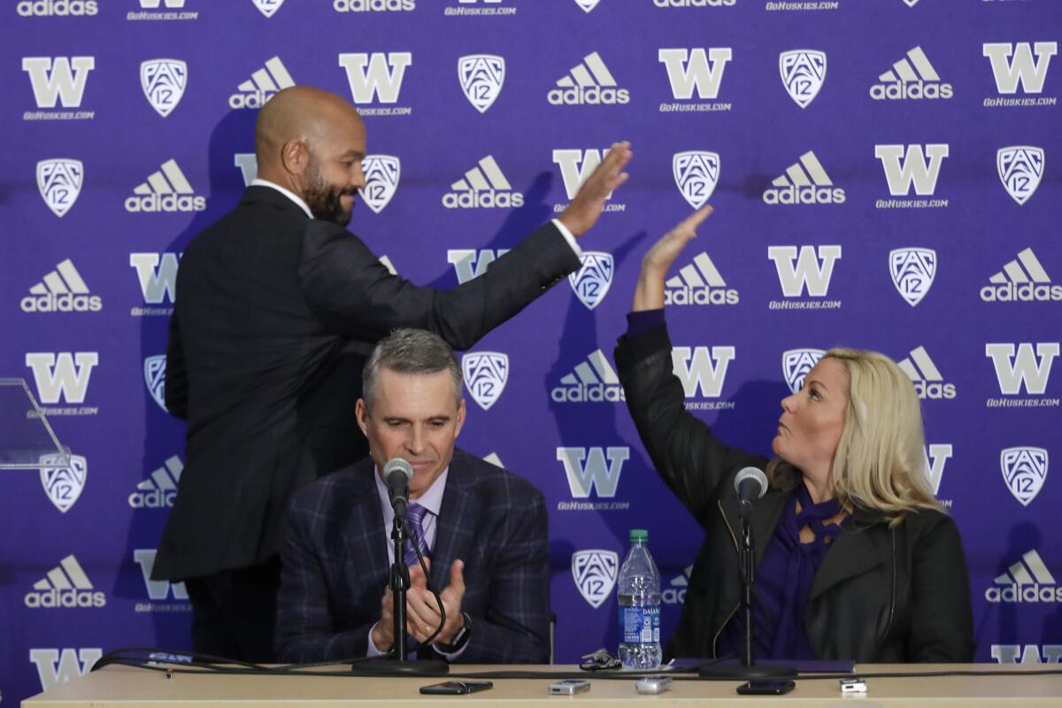 Washington coach Chris Petersen applauds as defensive coordinator Jimmy Lake high-fives athletic director Jennifer Cohen.