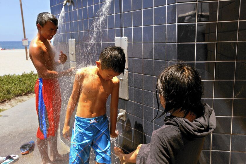 Outdoor showers like this one at Dockweiler State Beach -- being used by Ryanh Morales, left, and his brother Dereck as their sister Sophia stands by -- will be turned off at state beaches starting July 15.