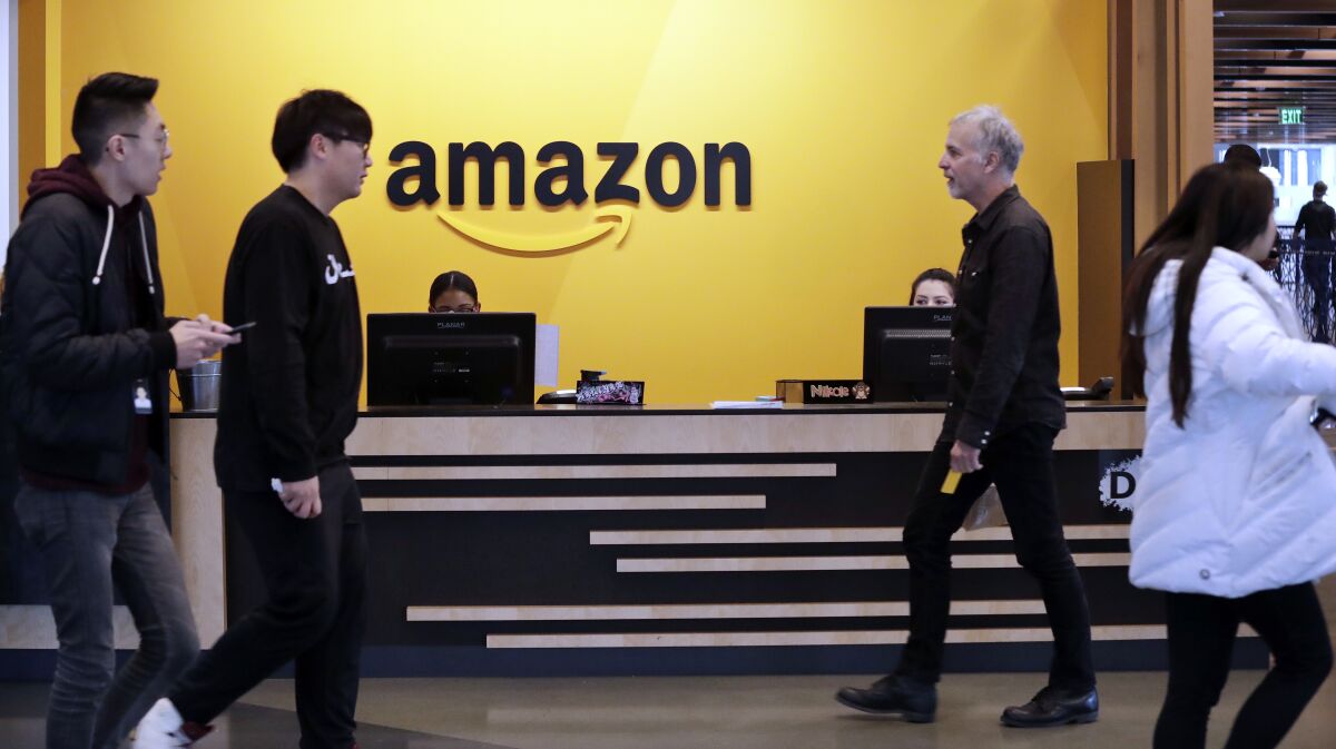 FILE - Employees walk through a lobby at Amazon's headquarters on Nov. 13, 2018, in Seattle. Amazon said Tuesday, March 15, 2022, it will spend more than $120 million to build affordable-housing units close to transit stations near Seattle and Washington, D.C, the latest example of a tech company trying to address the affordable housing crisis critics say the industry has exacerbated.(AP Photo/Elaine Thompson, File)