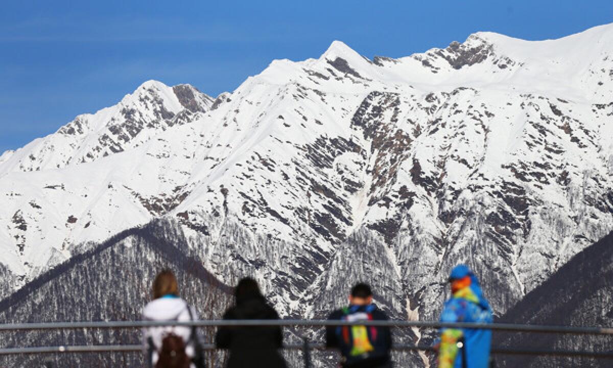 Spectators and volunteers enjoy the relatively warm weather during a training session at the Sanki Sliding Center in Sochi, Russia, on Wednesday. Warm weather has created problems at some of the Winter Olympic event venues.