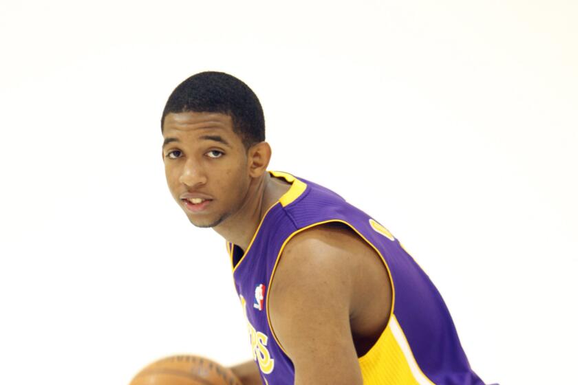 Darius Morris is holding a basketball and wearing his Lakers uniform