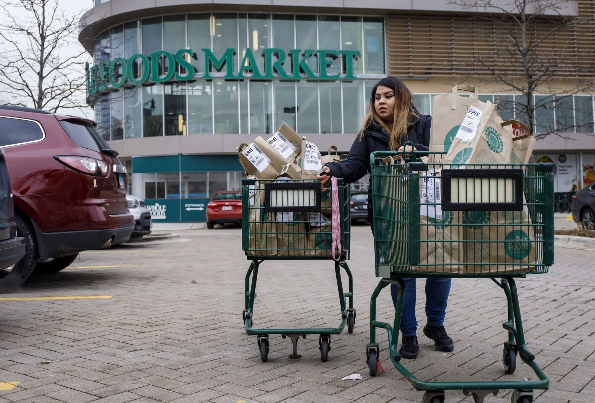 An Instacart worker transports orders for three customers to her car. 