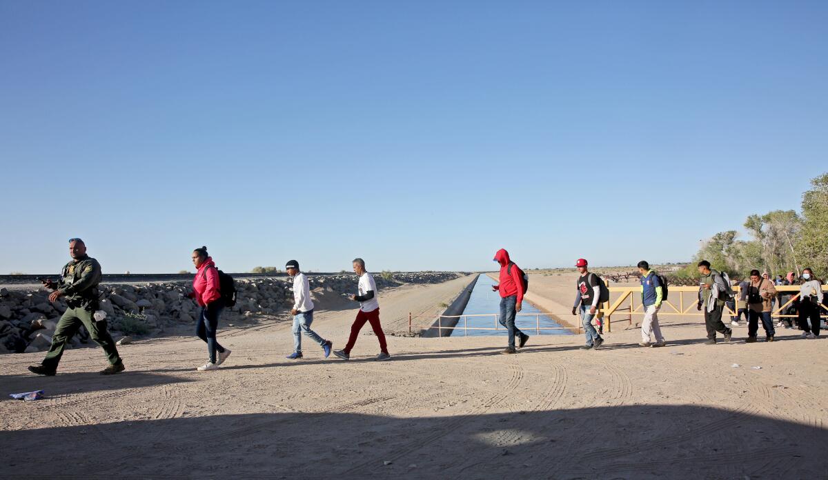 A line of people walk at the Mexico-U.S. border