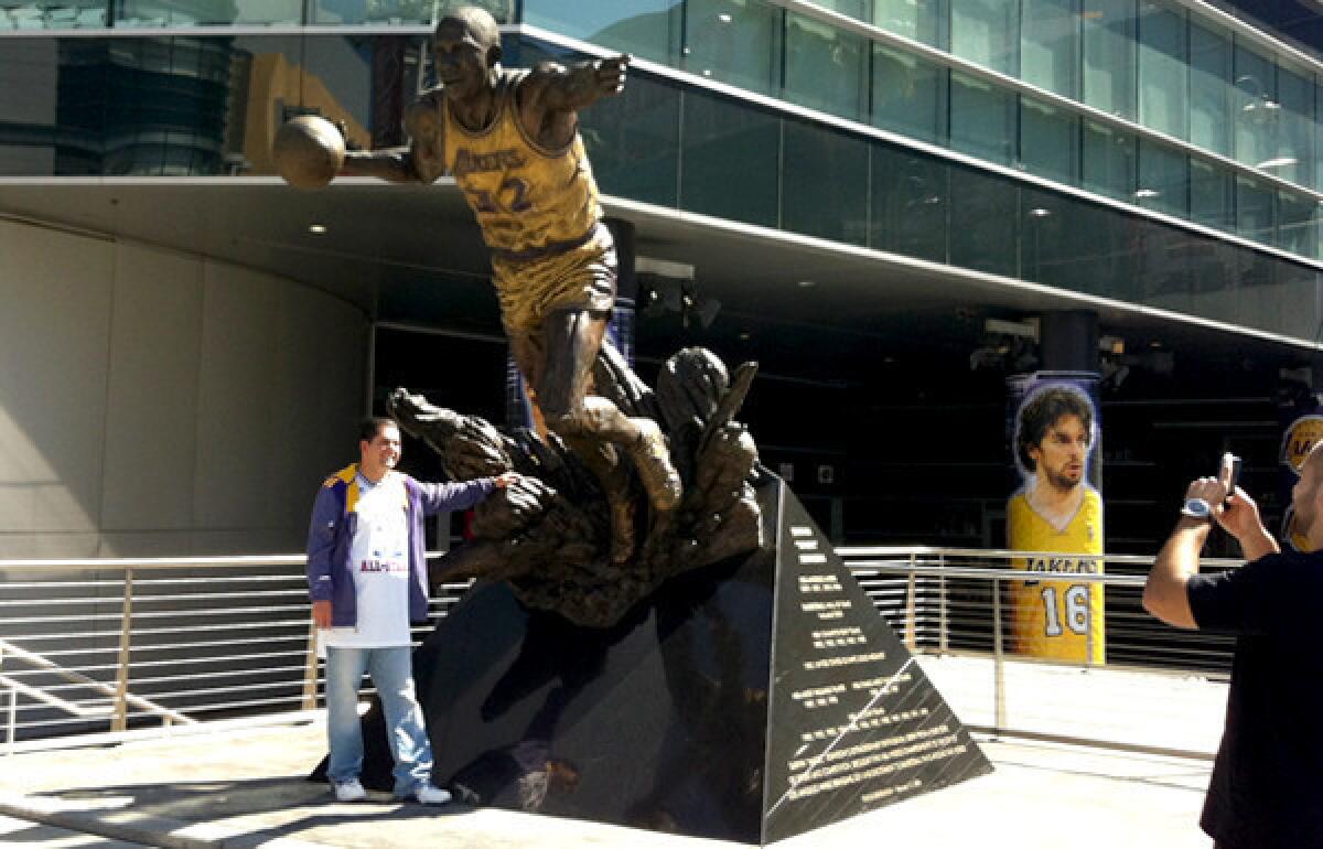 Lakers fan Luis Ramirez gets his photo taken at the Magic Johnson statue outside Staples Center on Wednesday evening.