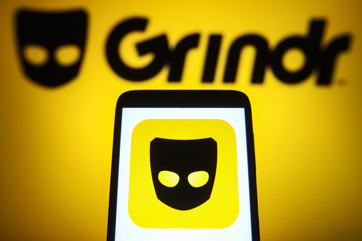 A Grindr logo is seen on a smartphone and a computer screen. 