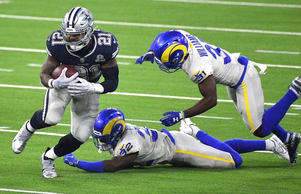 Cowboys running back Ezekiel Elliott eludes Rams defenders Jordan Fuller (32) and Darious Williams on Sept. 14, 2020.