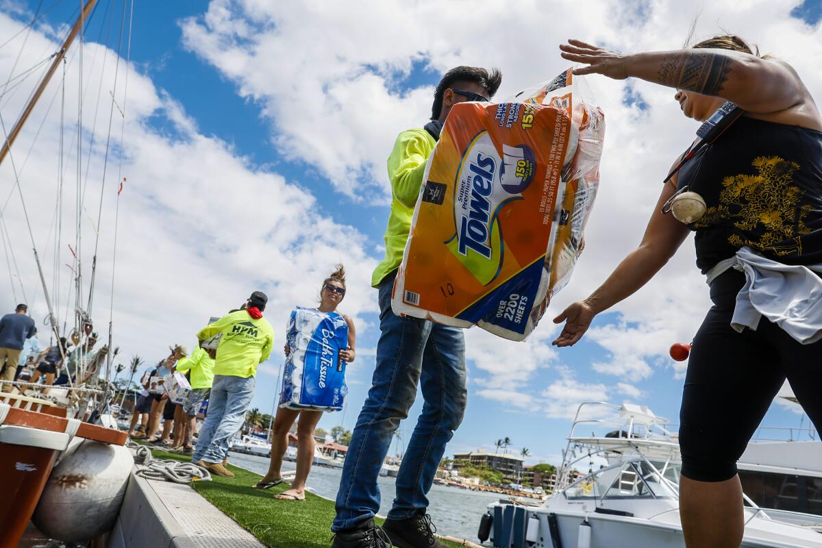 Supplies for Lahaina fire victims are passed by volunteers to be loaded on a boat for delivery