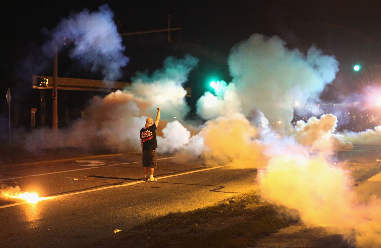 A demonstrator, protesting the shooting death of teenager Michael Brown, stands his ground as police fire tear gas in Ferguson, Mo.