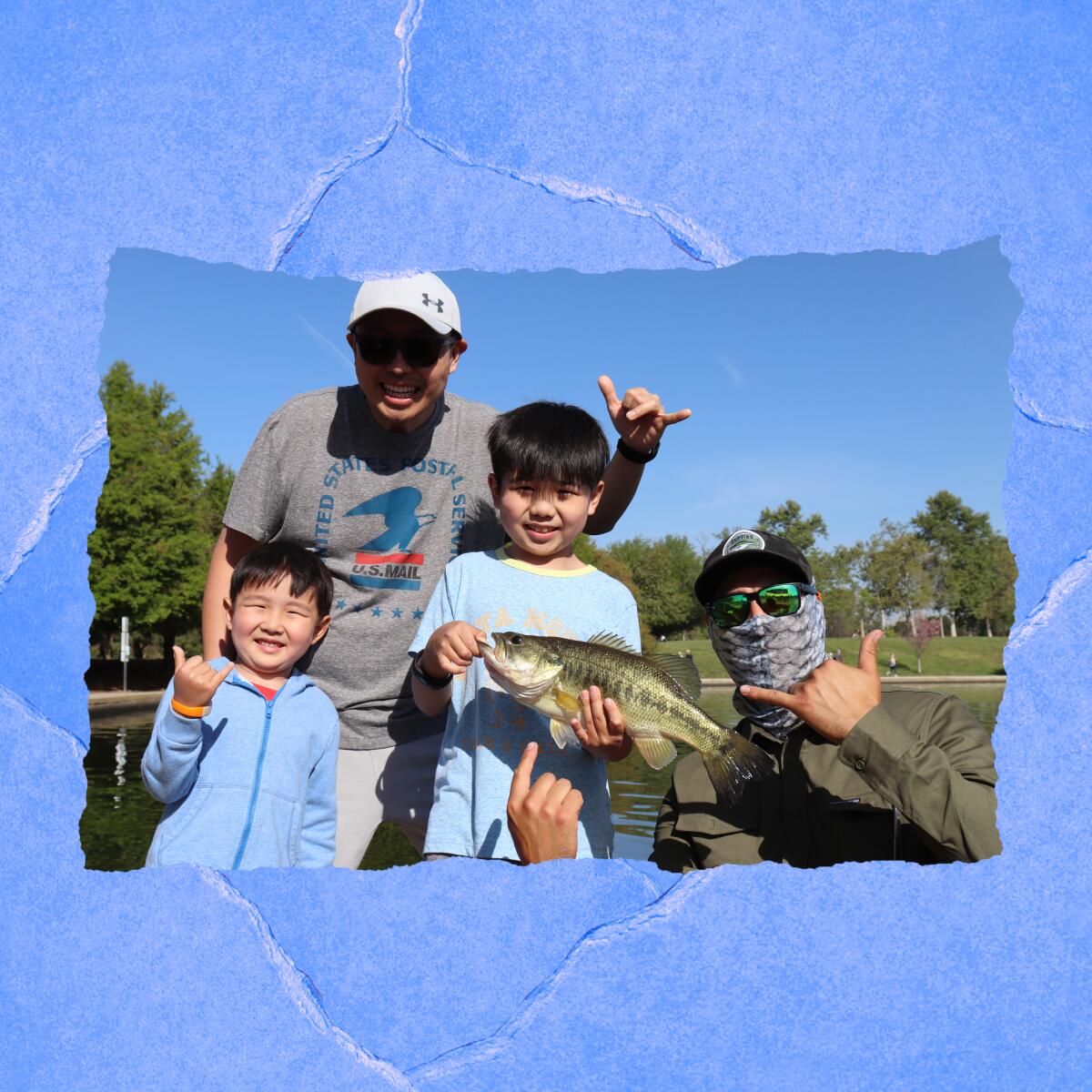 A boy holds a fish, next to a smaller boy and two adults