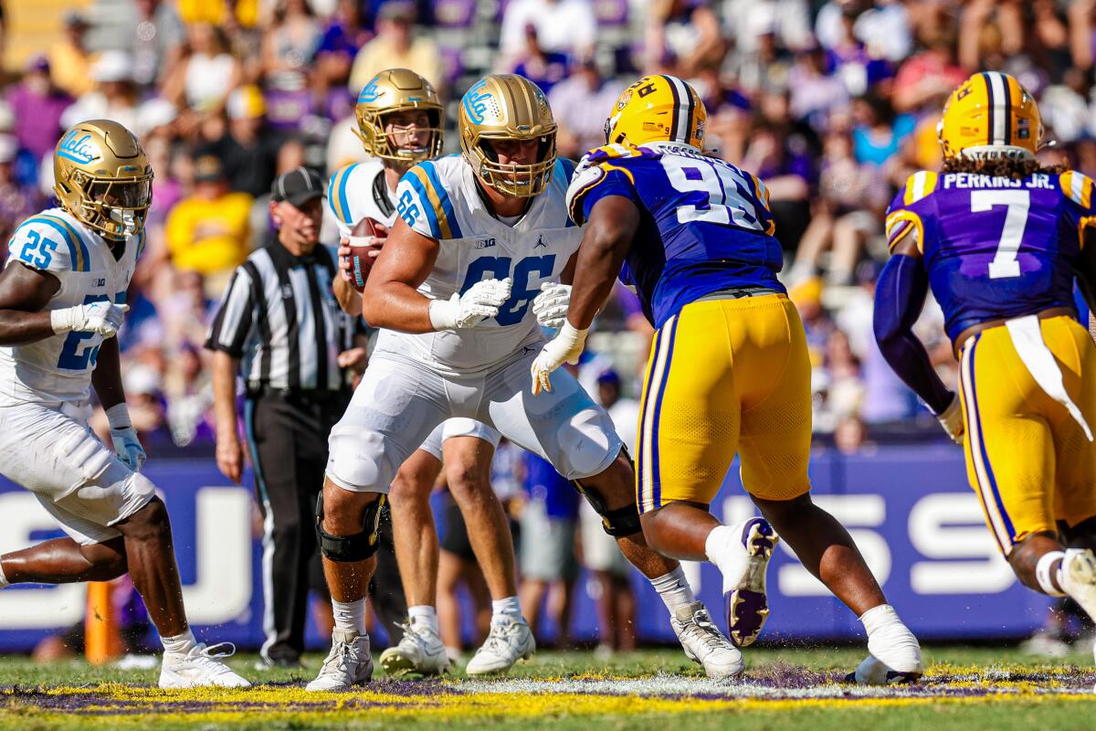 UCLA hücum yan hakemi Niki Prongos, LSU savunma yan hakemini bloklarken, oyun kurucu Ethan Garbers pas vermek istiyor