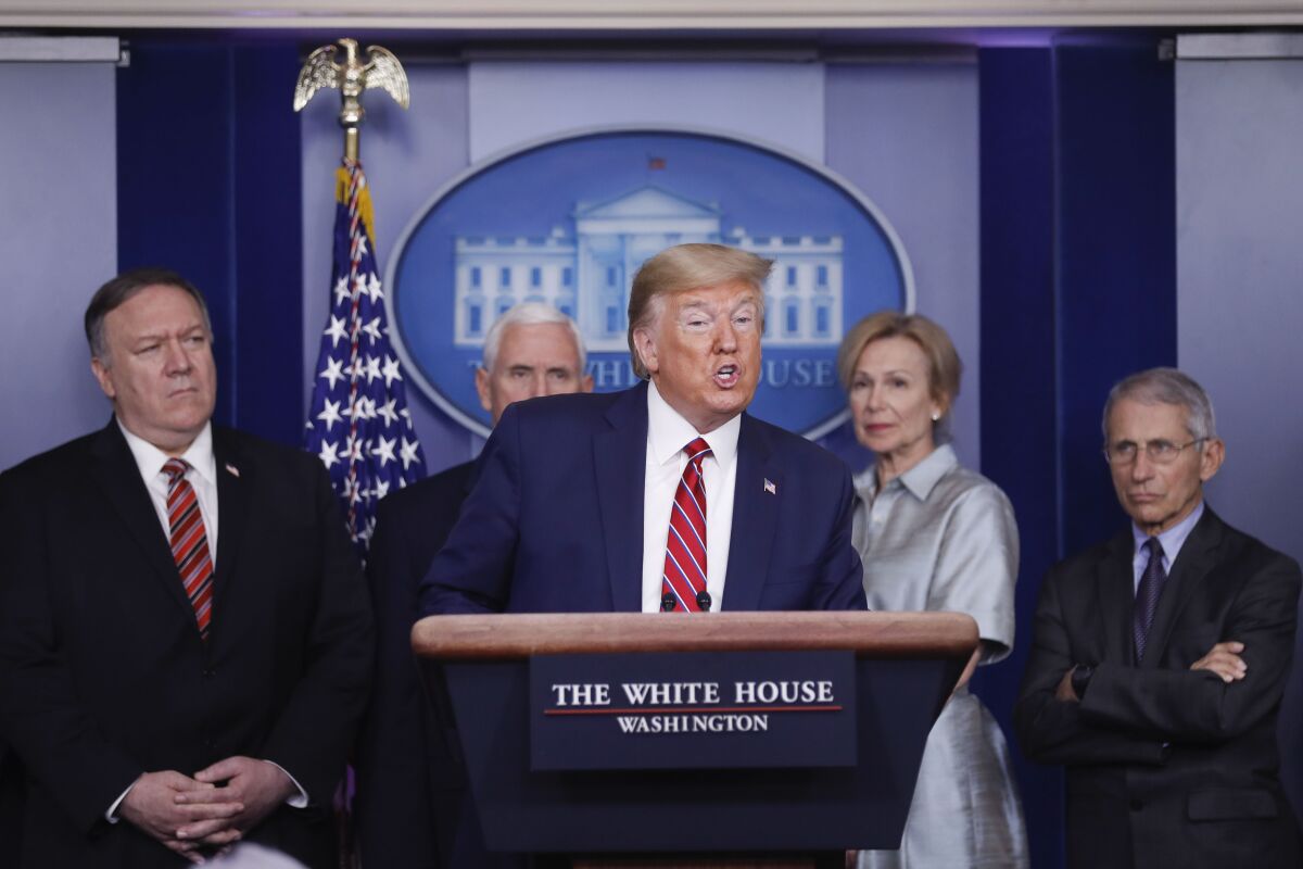 President Trump speaks at a news conference flanked by top officials.