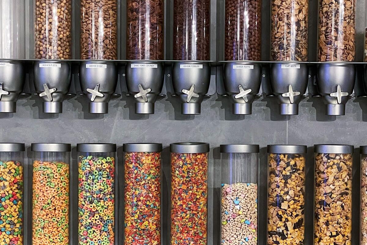 Two rows of clear cylinders containing various cereals for toppings at Kith Treats