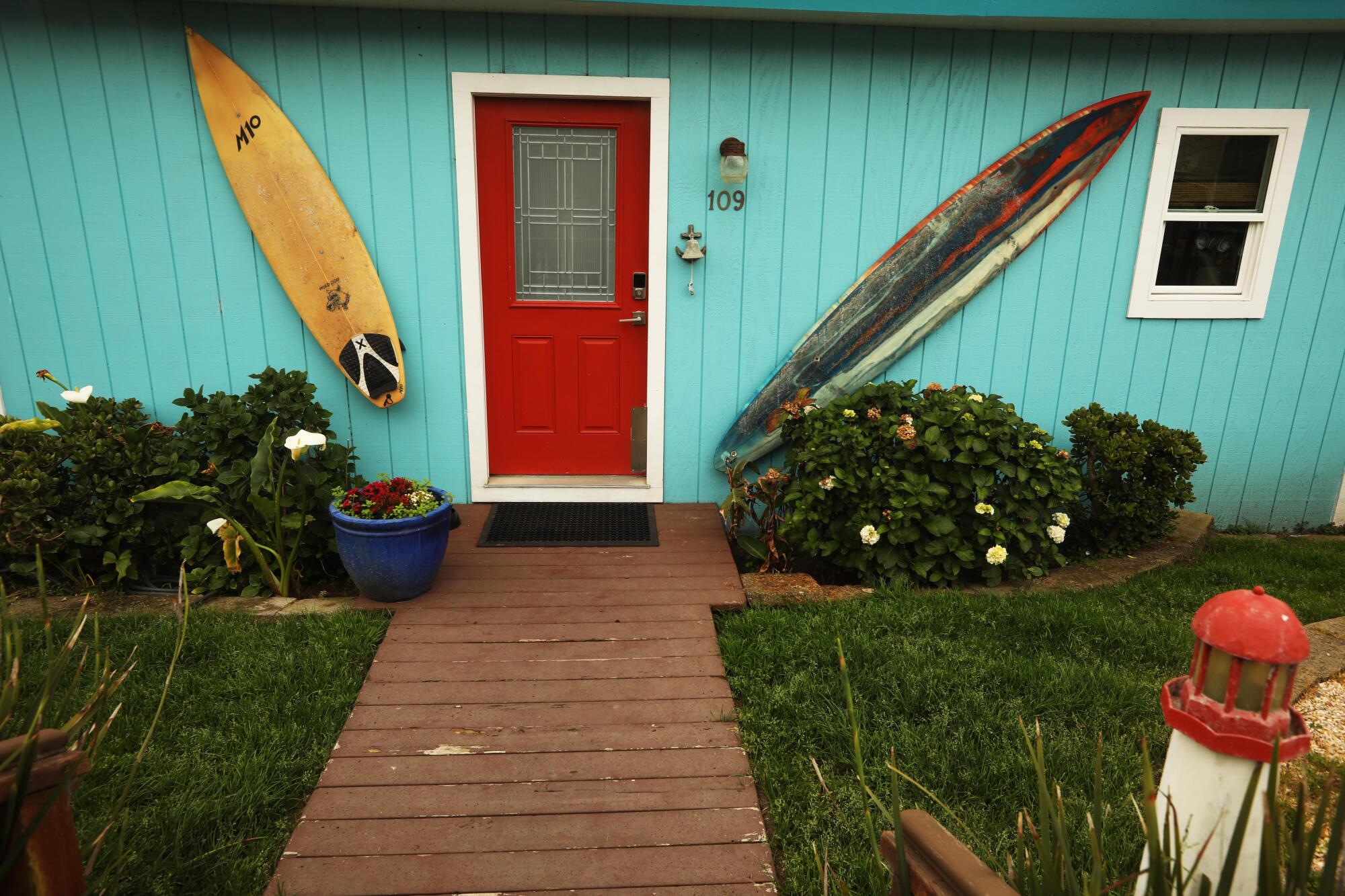 Colorful surfboards are mounted on a turquoise home.