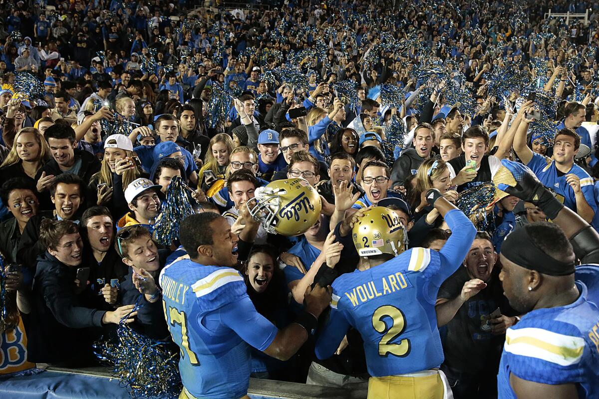 UCLA quarterback Brett Hundley and teammate Asiantii Woulard cheer with Bruins fans after beating USC, 38-20, at the Rose Bowl.