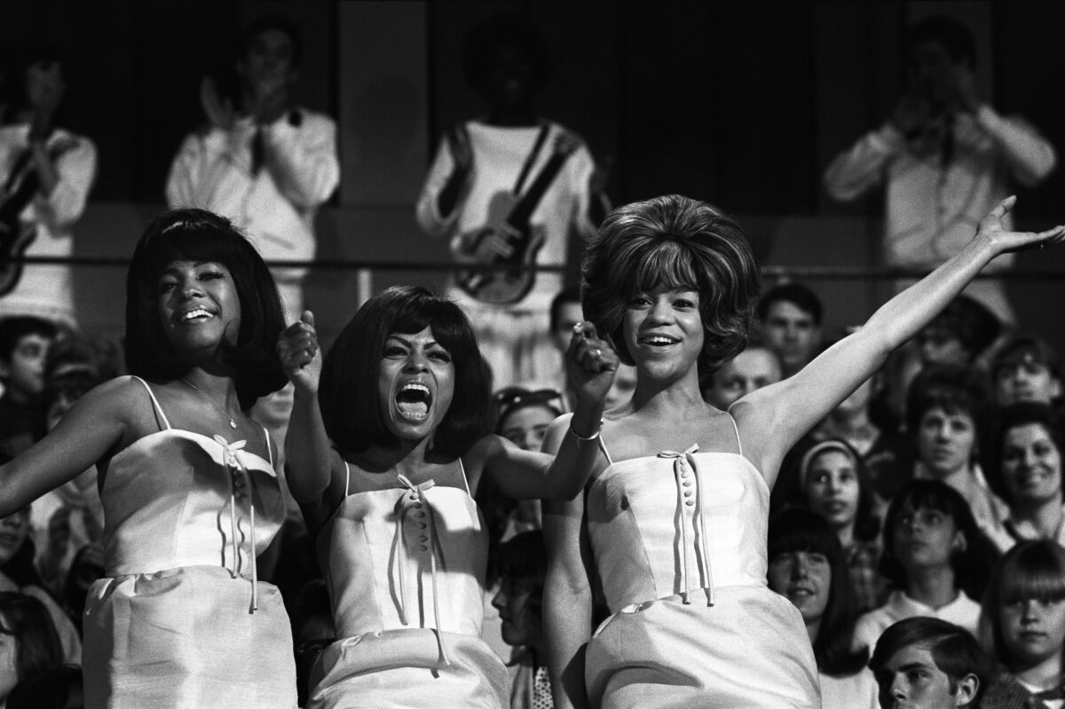 A black-and-white image of the Supremes wearing matching white dresses