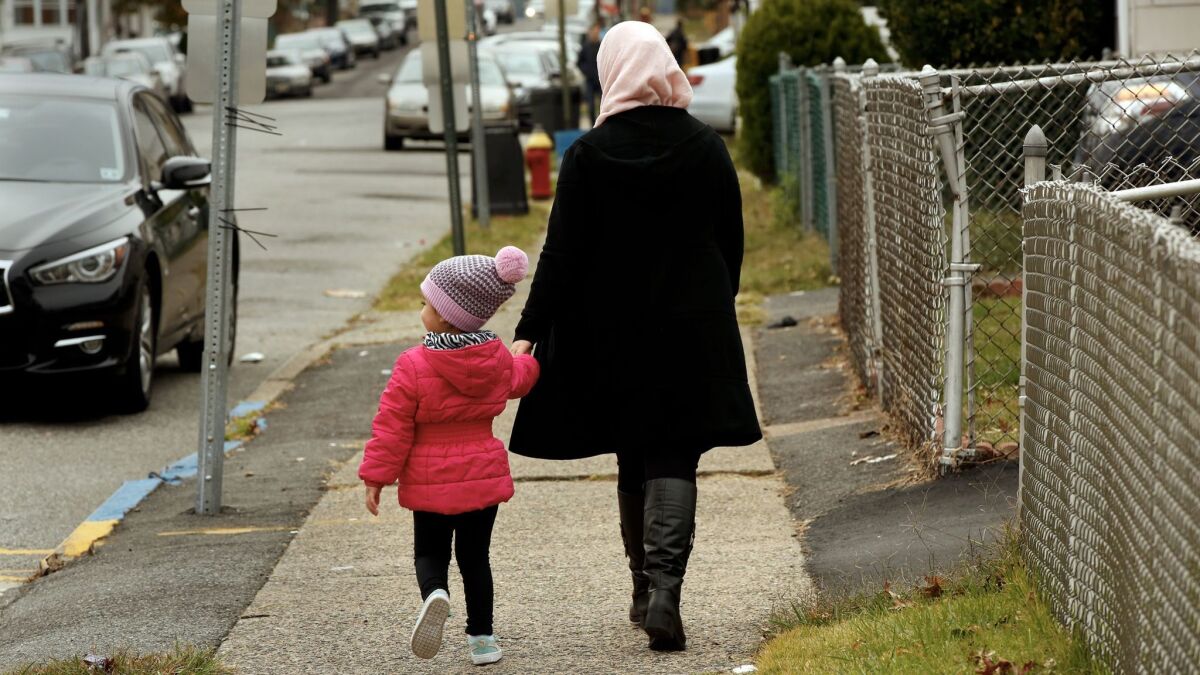 A woman walks with her child on the street where Sayfullo Saipov lived.