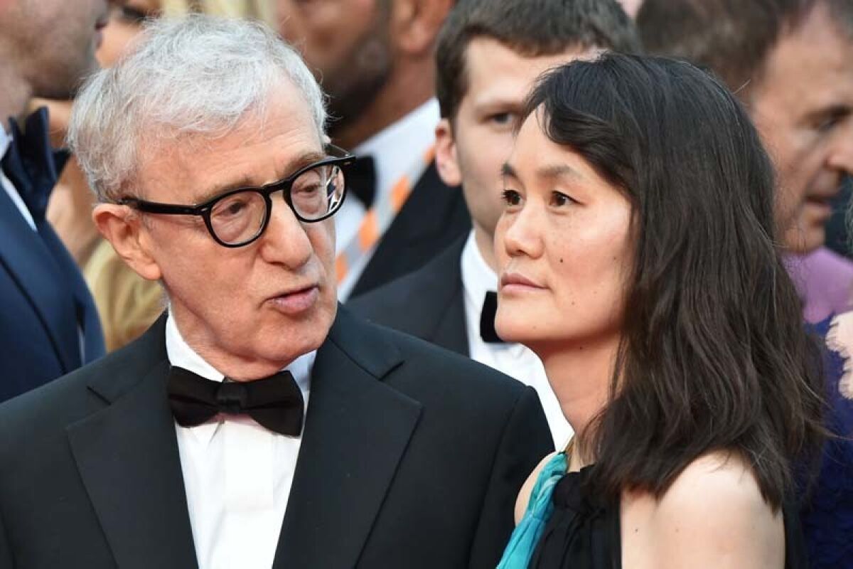 Woody Allen in a tuxedo and glasses with Soon-Yi Previn in a blue and black dress