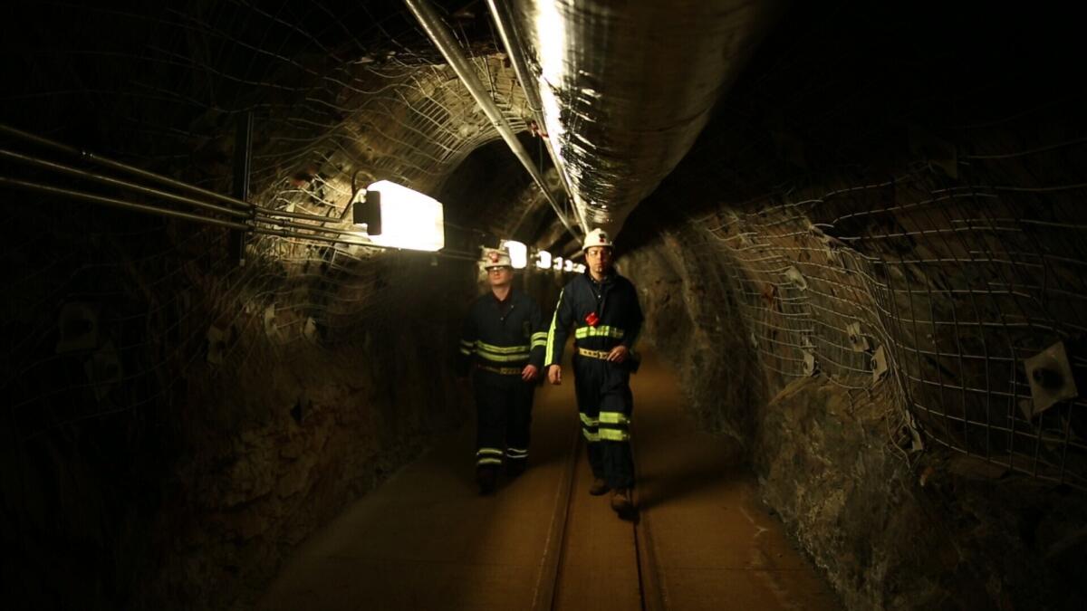 Two researchers walk through an old mining tunnel to what is now the Sanford Underground Research Facility in Lead, S.D., on Dec. 8, 2019. The laboratory houses a dark matter detector. Scientists have begun a new search for mysterious dark matter in a former gold mine a mile underground. Dark matter makes up the vast majority of the mass of the universe but scientists don't know what it is. (AP Photo/Stephen Groves)