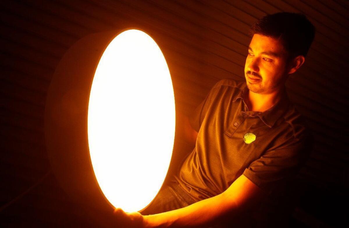 Robert Soler, co-founder of Bios, holds a light that has the natural daylight spectrum of the planet Mars, which he designed for the Mars Experience exhibit at the Wings of Eagles Discovery Center in New York.
