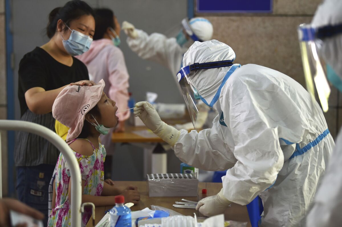 A nurse takes swab samples in the new rounds of Covid-19 testing in Nanjing in eastern China's Jiangsu province Monday, Aug. 2, 2021. China's worst coronavirus outbreak since the start of the pandemic a year and a half ago escalated Wednesday, Aug. 4, 2021 with dozens more cases around the country, the sealing-off of one city and the punishment of its local leaders. (Chinatopix Via AP)