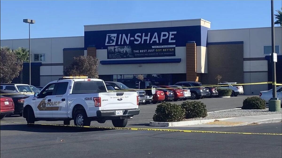 Police tape and a police vehicle are seen outside a building with the sign In-Shape.