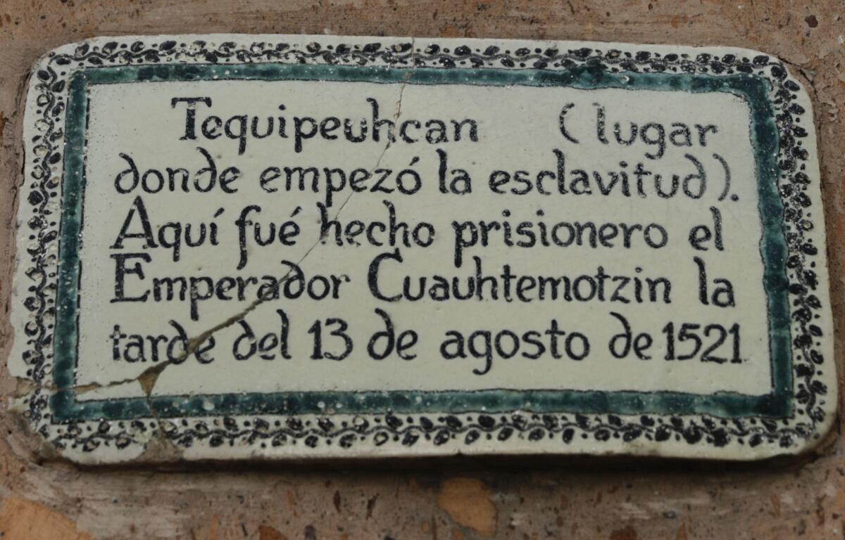 A plaque with a green and black border with black letters in Spanish against a white background