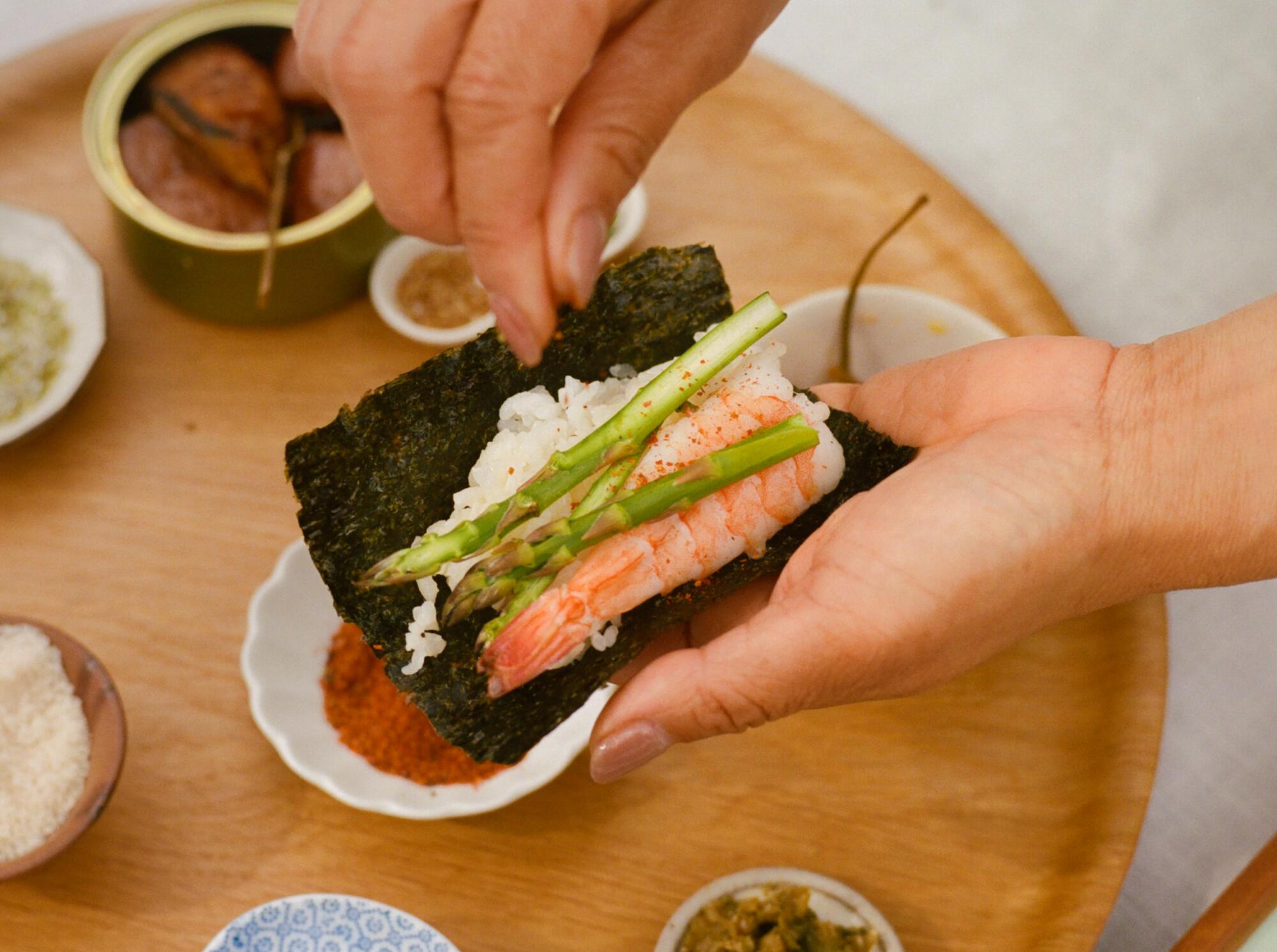 A poached shrimp with asparagus hand roll, sprinkled with sesame seeds
