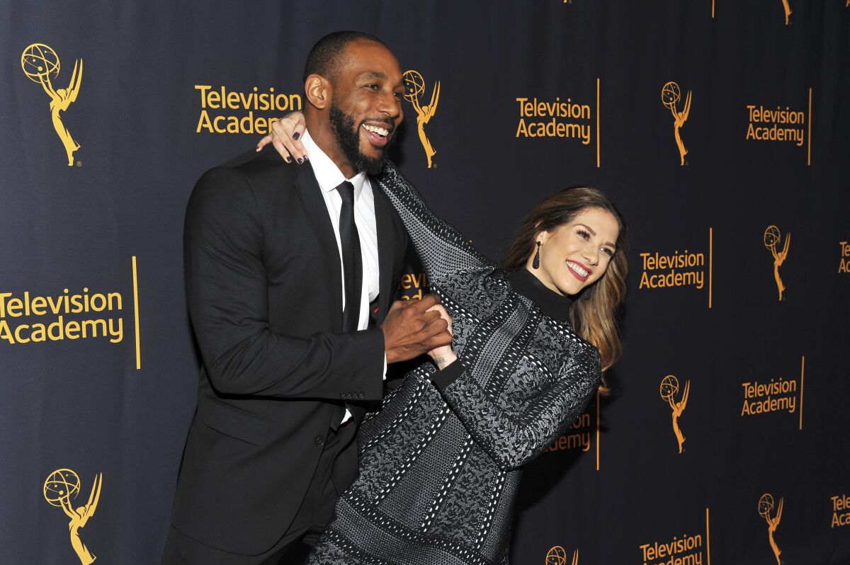 A man and a woman posing as if he's dipping her at an event's red carpet.