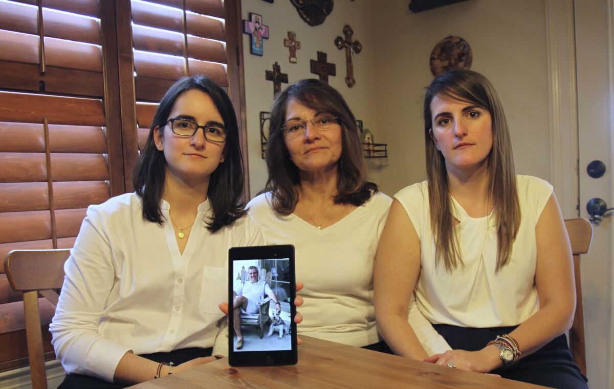 FILE - Dennysse Vadell sits between her daughters Veronica, right, and Cristina, Feb. 15, 2019, in Katy, Texas, while holding a digital photo of father and husband Tomeu Vandell, who was jailed in Venezuela at the time. Vadell, one of the six oil executives with Texas-based Citgo who was held for nearly five years in Venezuela before being released in 2022, sued his company Tuesday, March 21, 2023, for $100 million, alleging it abandoned him and his family as he wasted away in horrific prison conditions for a crime he did not commit. (AP Photo/John L Mone, File)