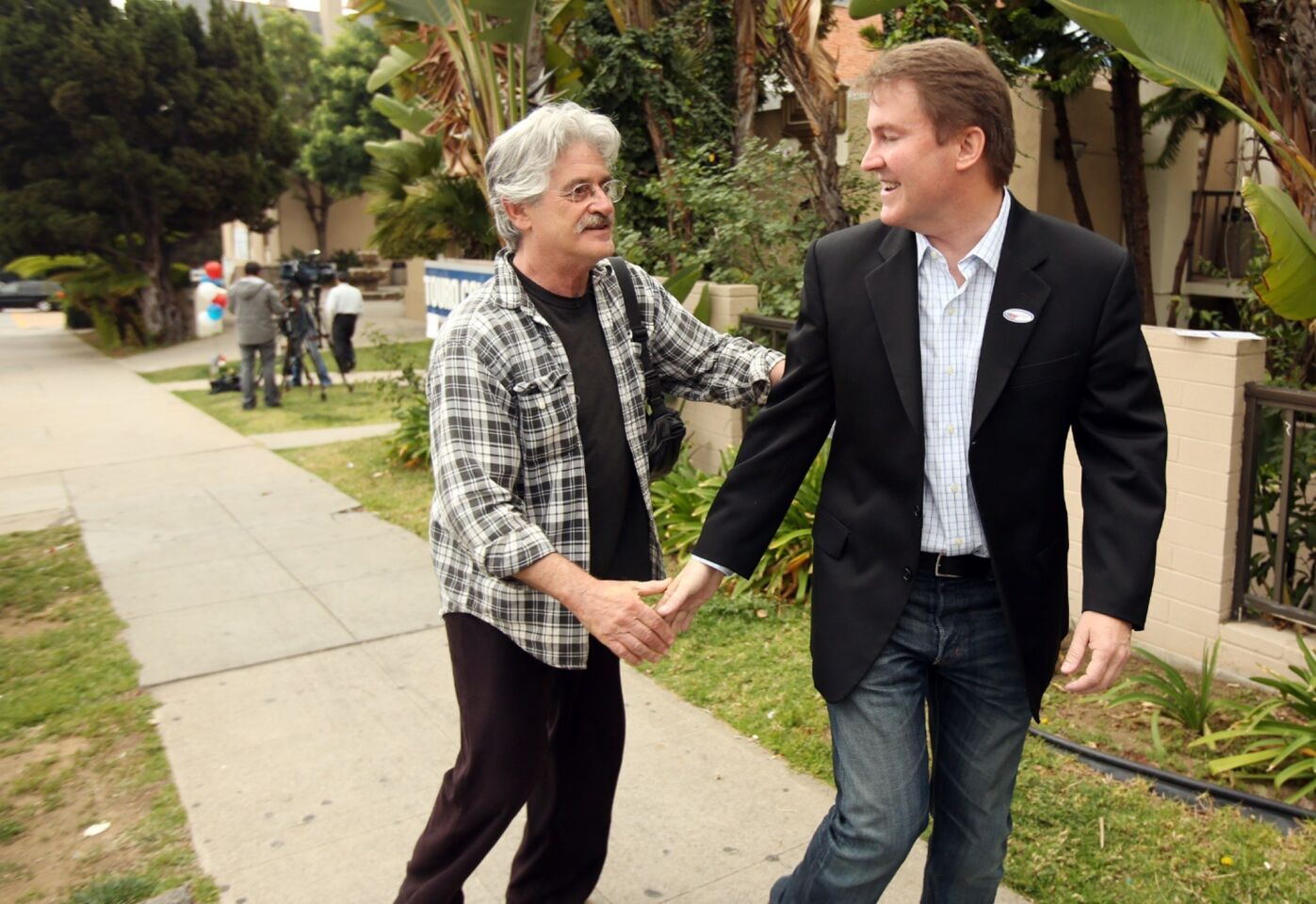 Mayoral candidate Kevin James, right, gets a handshake from Skip Haynes, a Laurel Canyon neighbor, after casting his ballot at the Hollywood Temple Beth El in West Hollywood.