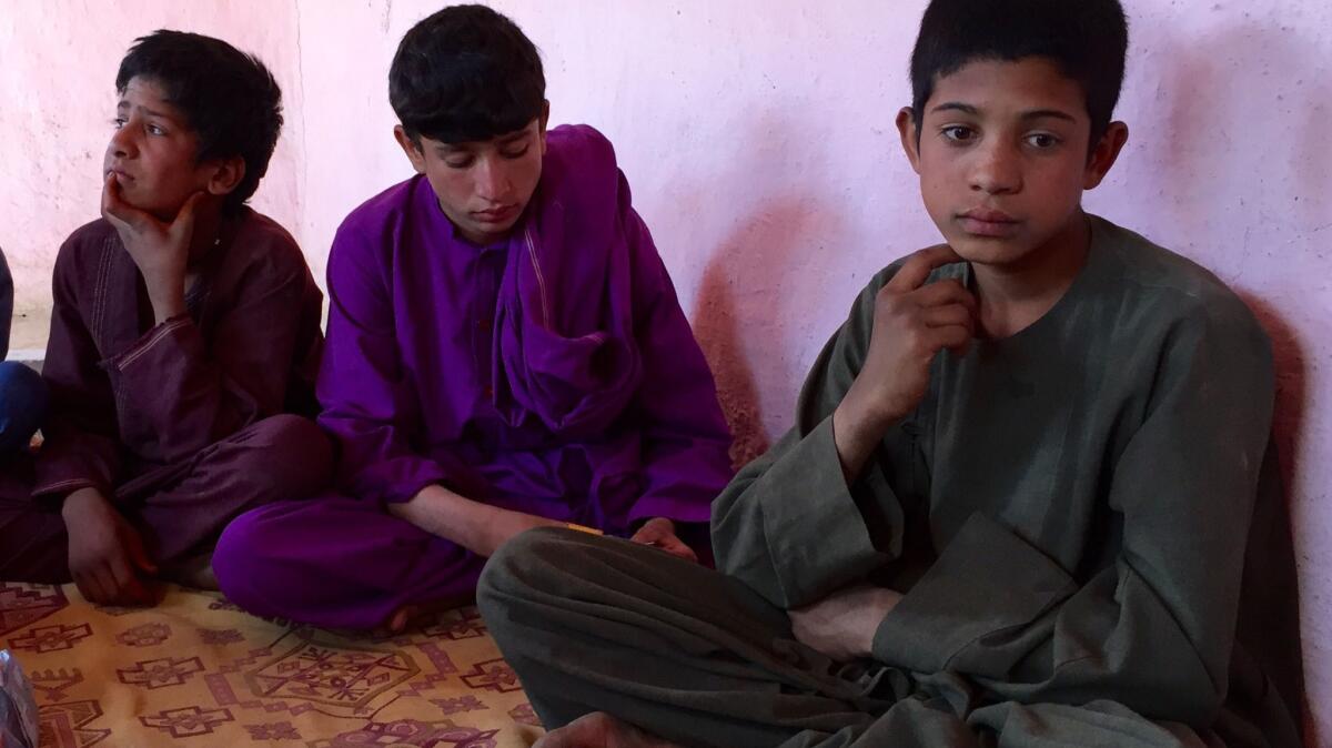 Wakil, 14, right, polishes shoes to help his family make ends meet at a camp for displaced people in Kabul.