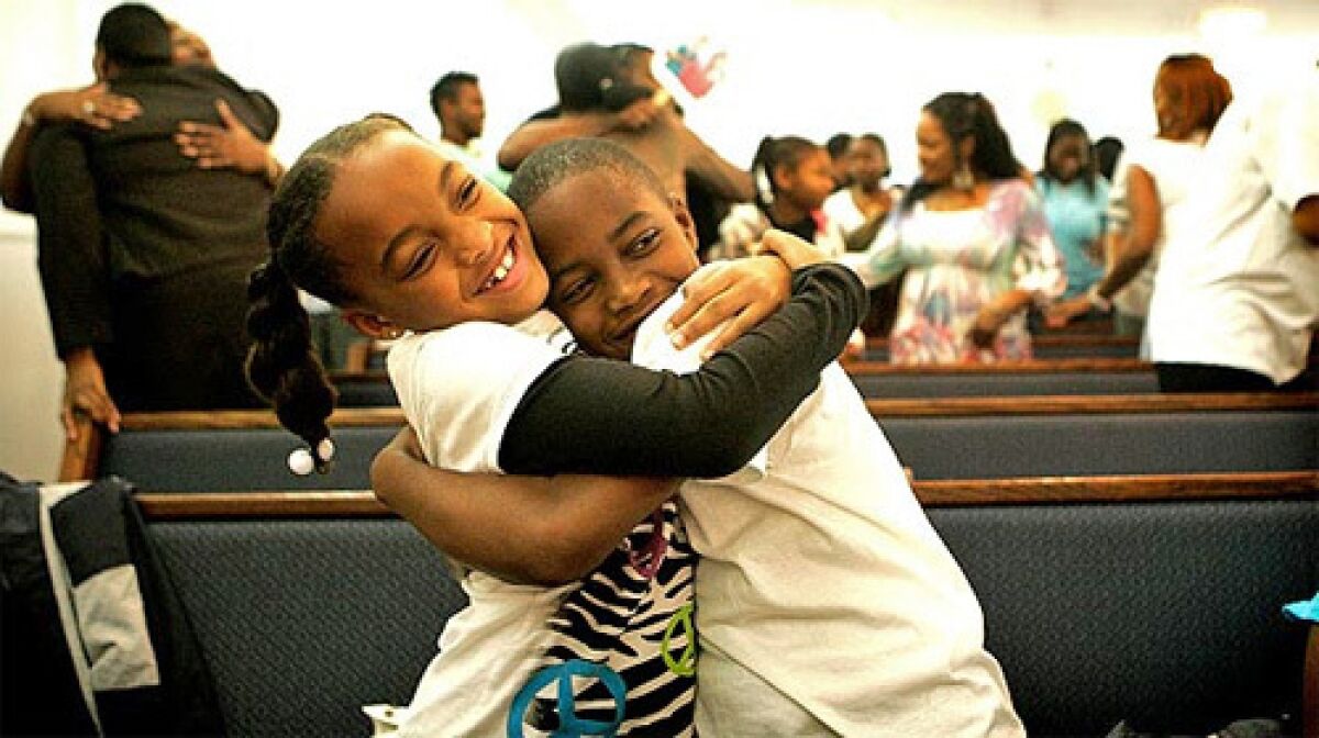 Children embrace at a Compton church event in January. Faith Inspirational Missionary Baptist Church offers free movies in local parks, and draws large crowds as people feel safer going out.