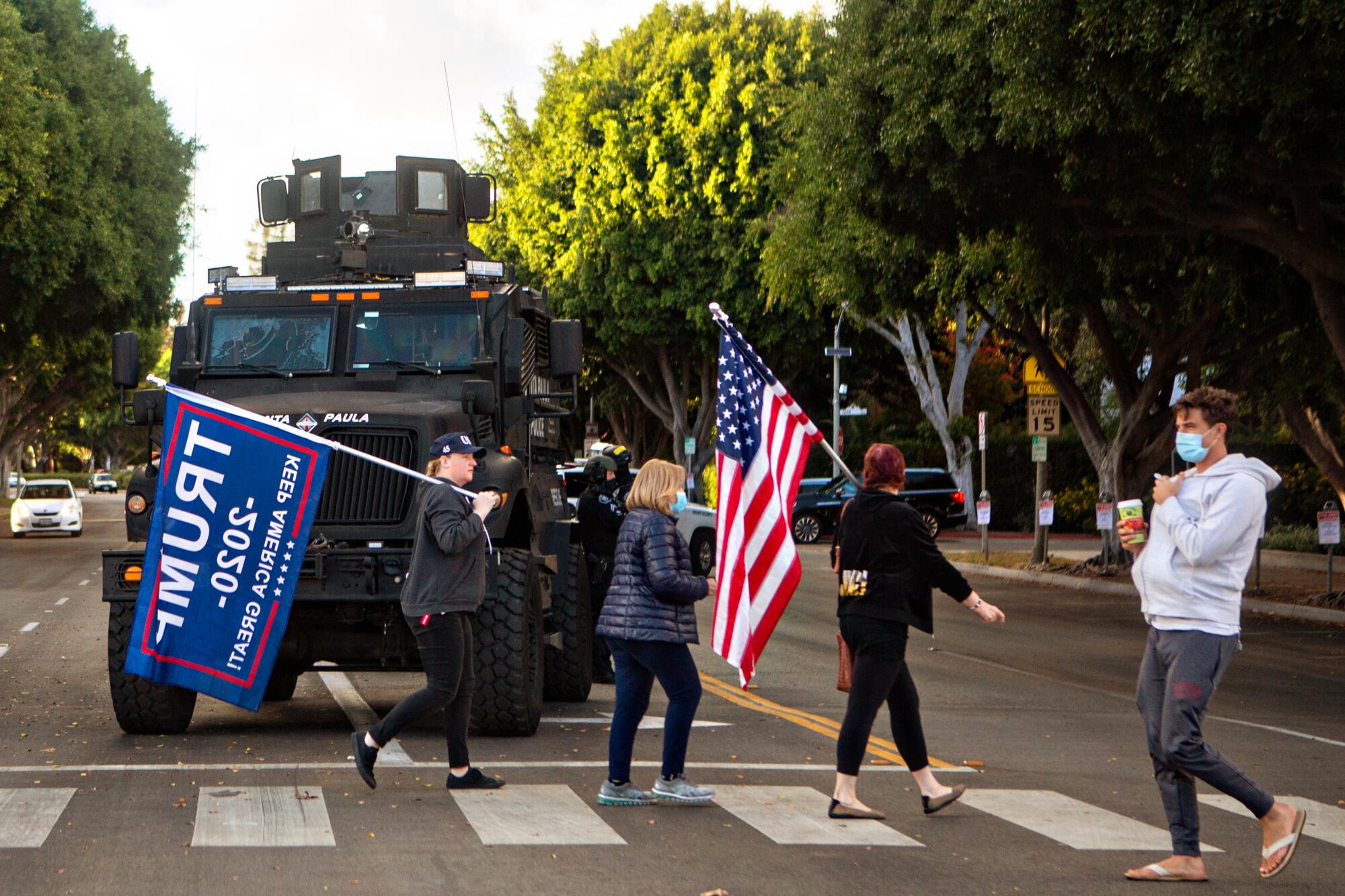President Trump supporters walk past riot-control police vehicles on their way to a rally in Beverly Hills.
