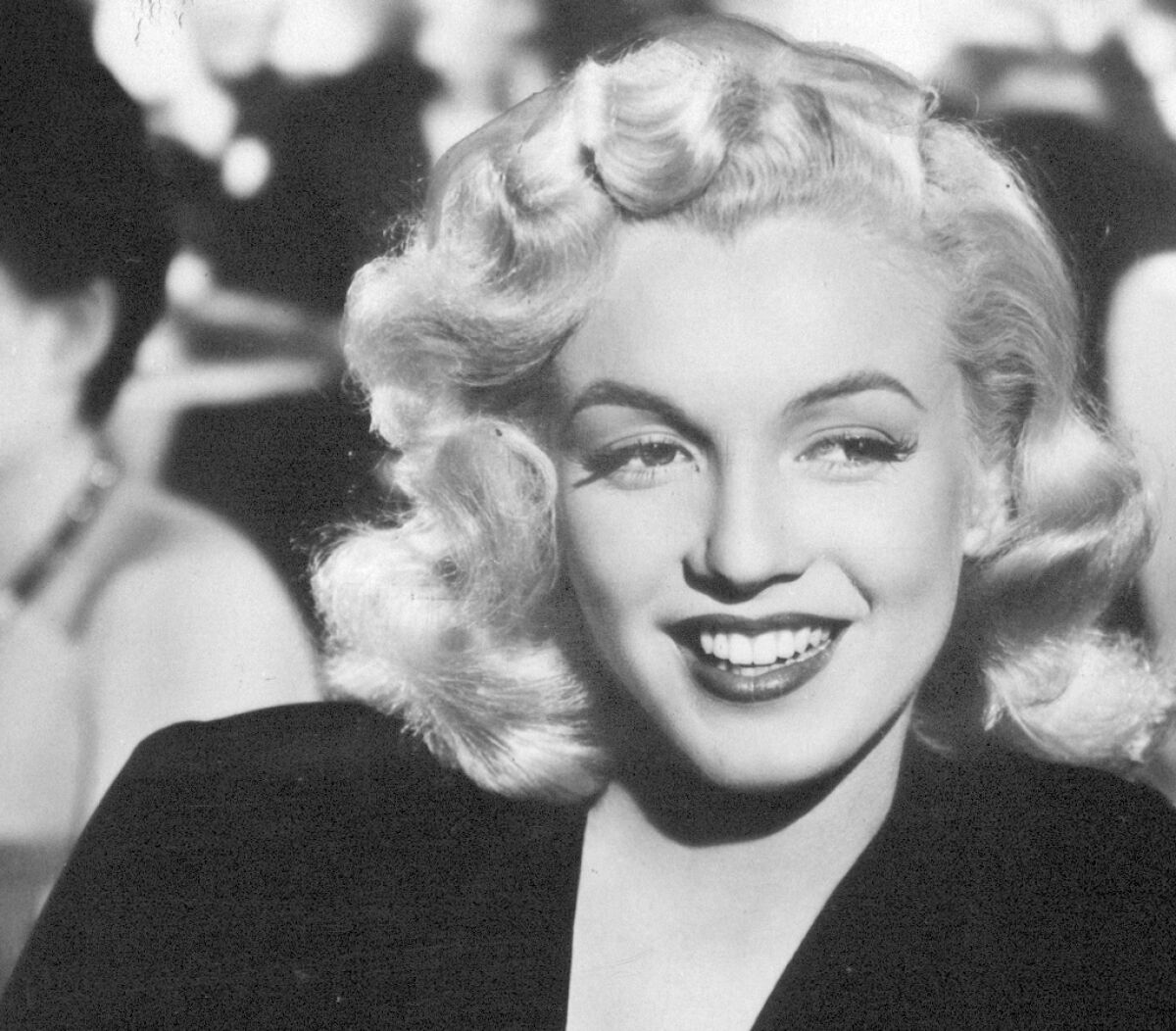 Closeup of a blond woman in a black dress.