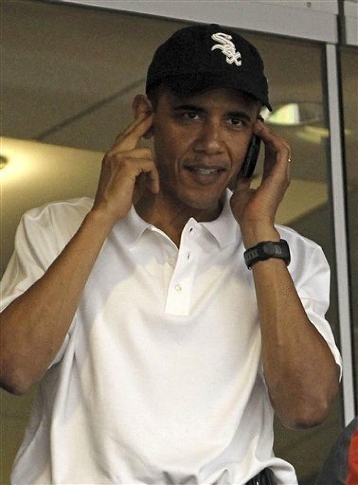 President Barack Obama, wearing a Chicago White Sox hat, talks on a phone during a baseball game between the Washington Nationals and Chicago White Sox, Friday, June 18, 2010, in Washington. (AP Photo/Haraz N. Ghanbari)
