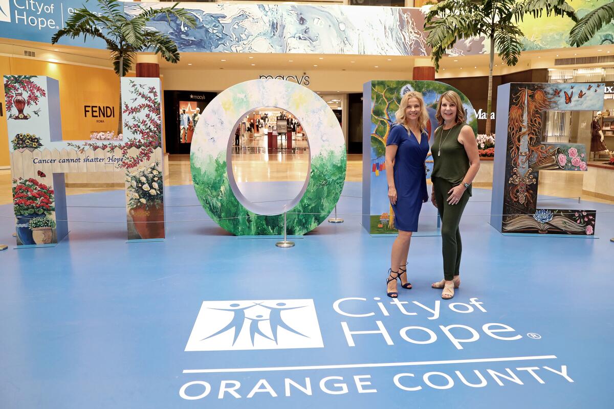 Kamila Kowalke, left, and Cindy Brown stand in front of "Hope is a Masterpiece" display.