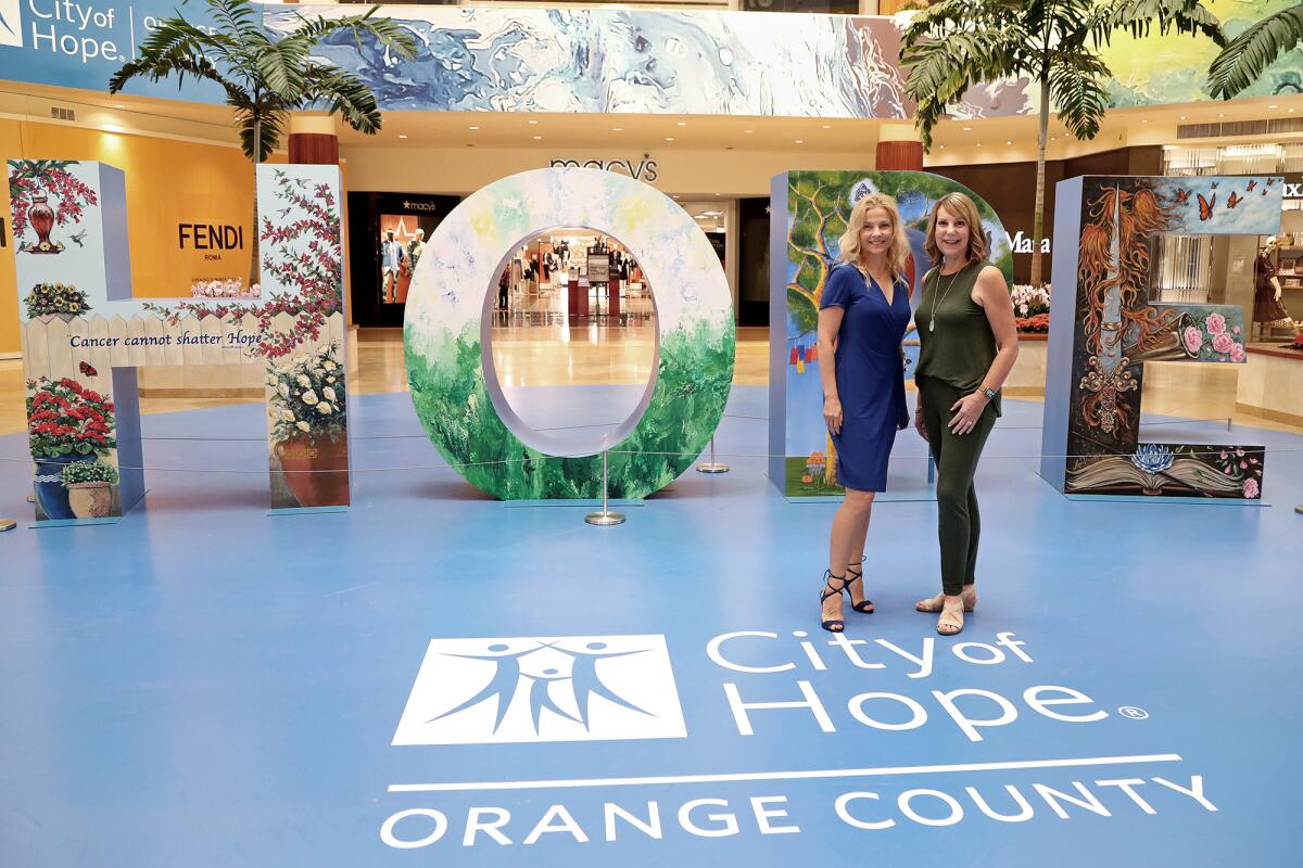  Kamila Kowalke, left, and Cindy Brown stand in front of "Hope is a Masterpiece" display.