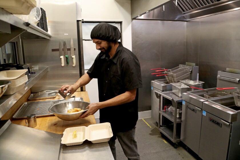Chef and co-owner Arjun Neil Bhakta seasons some chips at London Chippy.