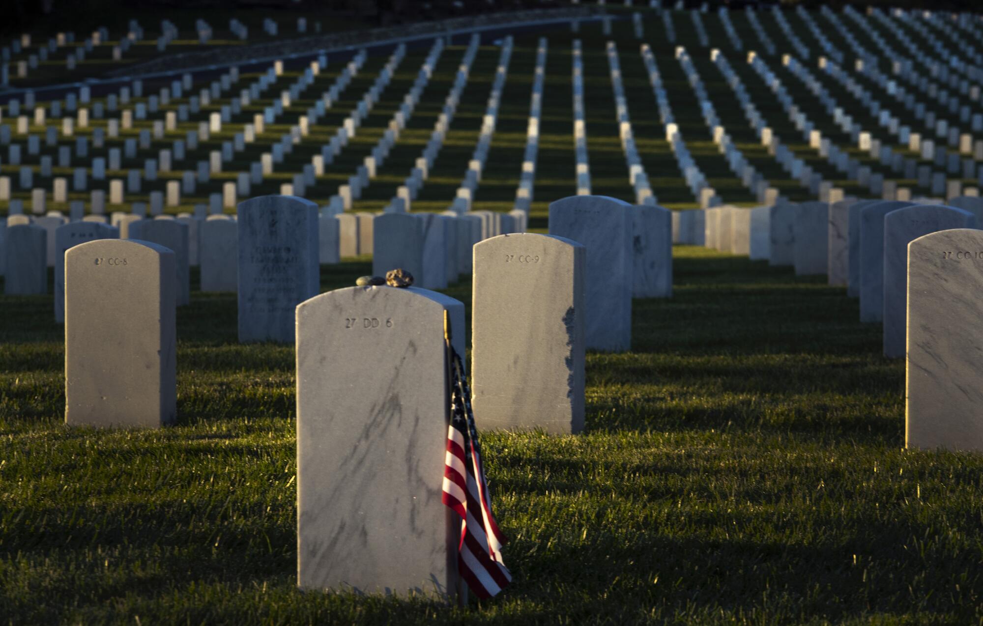 A lone American flag catches the last rays of light as the sun sets on the Los Angeles National Cemetery.